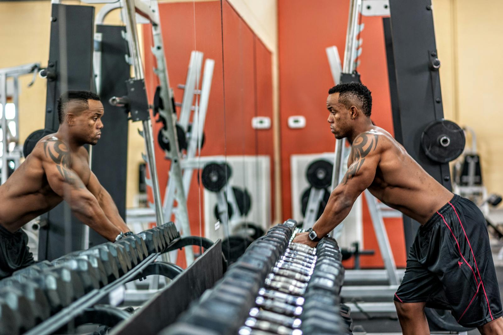 Muscular man exercising with dumbbells in gym, emphasizing strength and fitness.