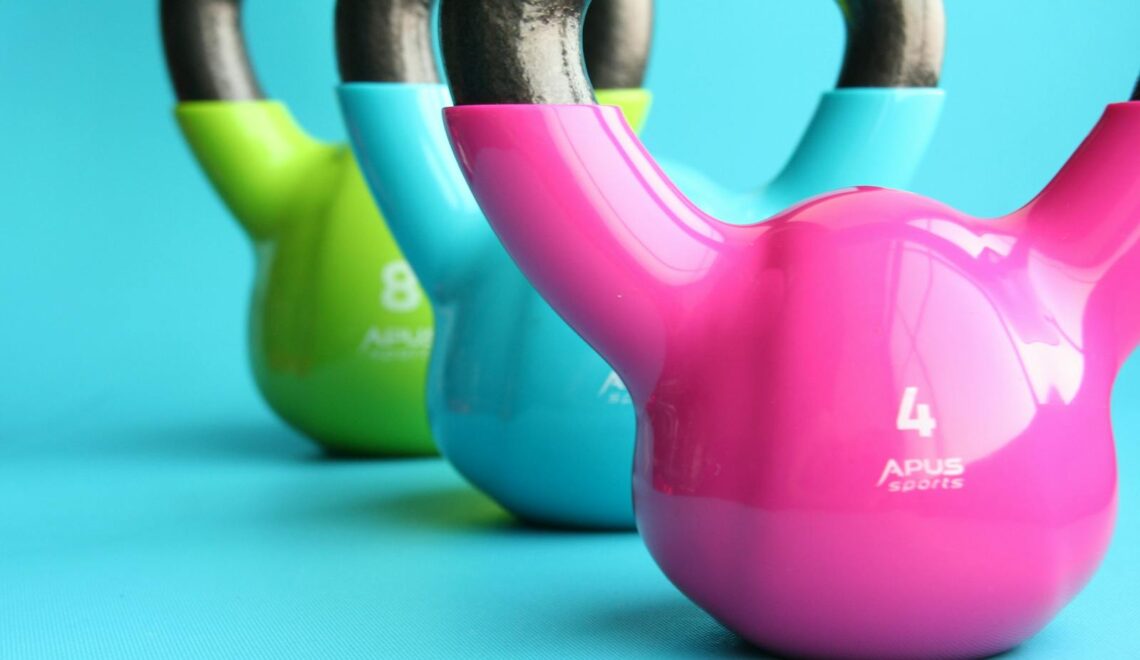 Vibrant colored kettlebells on blue background highlighting fitness and exercise equipment.