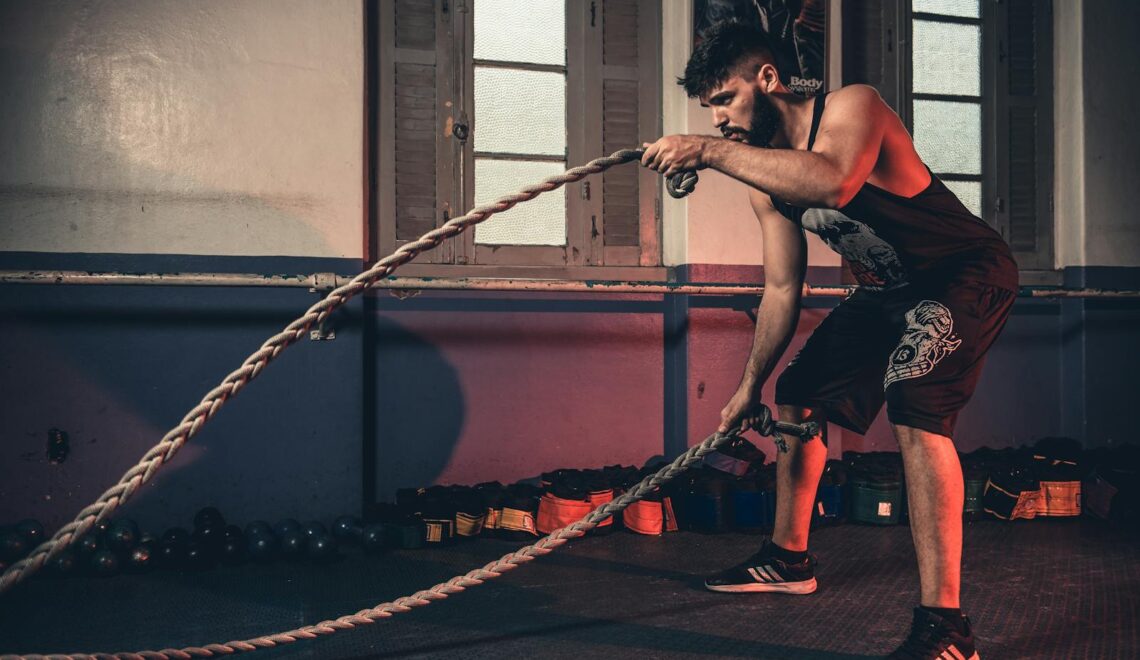 Man performing a challenging Crossfit rope exercise in an indoor gym setting.