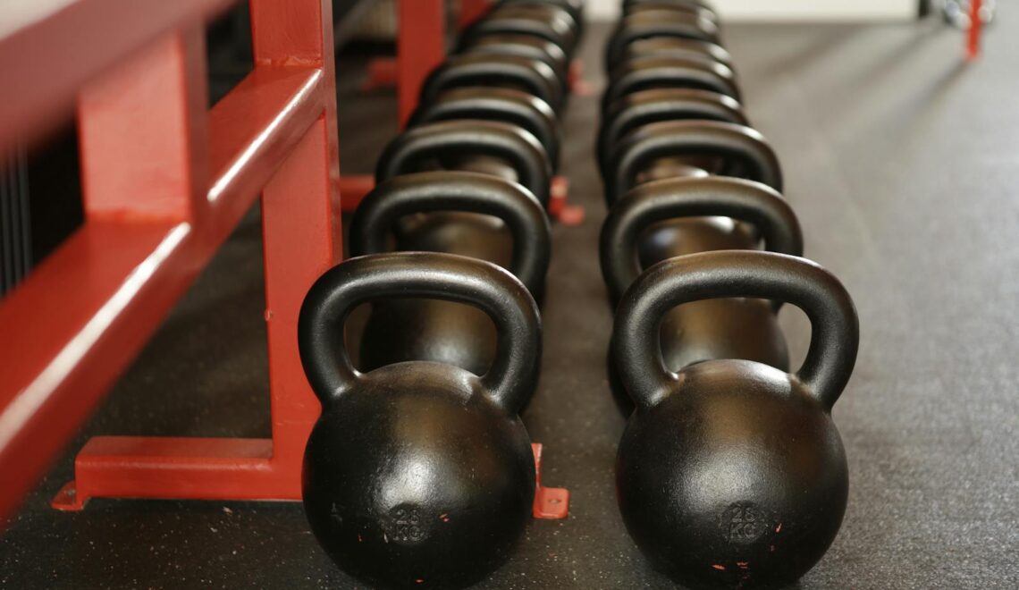 Black kettlebells lined up in a gym, ready for fitness training.