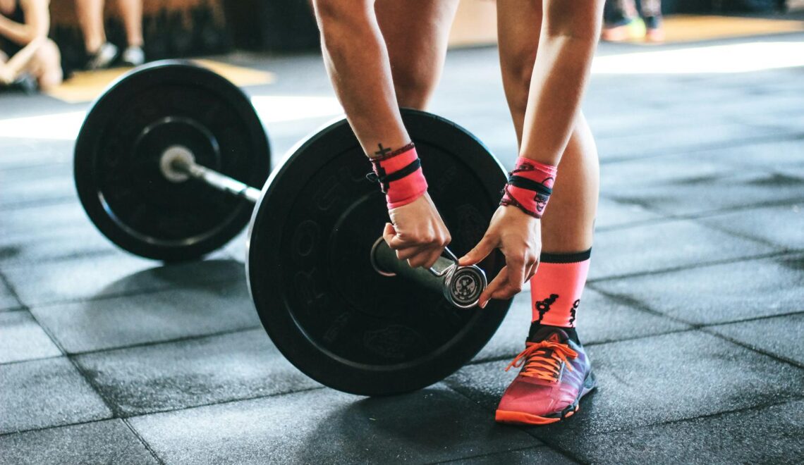 Athlete tightening barbell plates in a gym, emphasizing fitness and strength.