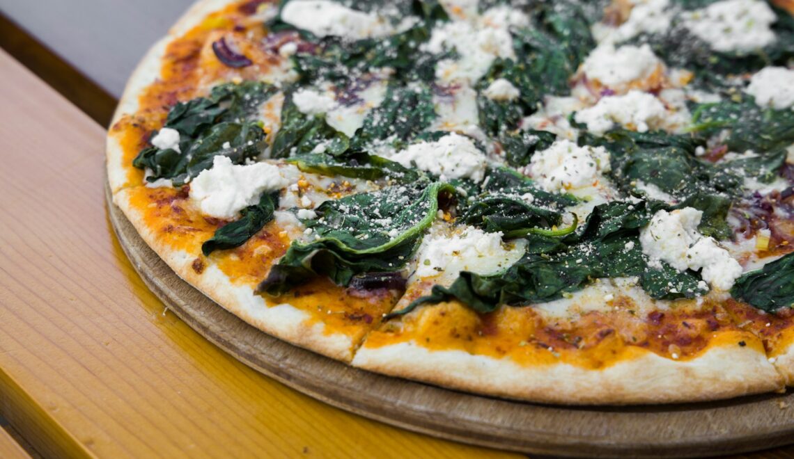 pizza with green leaves on brown wooden table