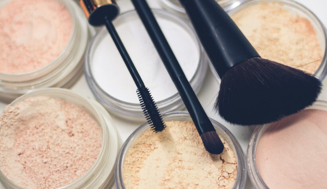 three makeup brushes on top of compact powders