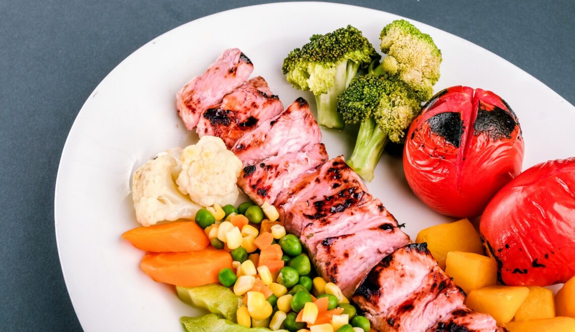 grilled meat with green vegetable and red chili on white ceramic plate